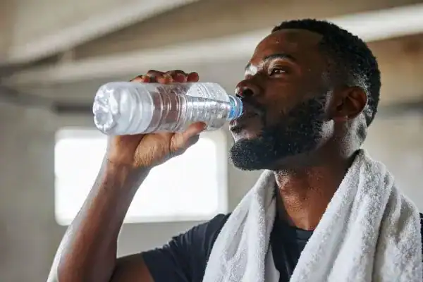 Hydration: The Secret Ingredient for a Toned Stomach and Enhanced Fitness 1 Image of man drinking water to improve hydration Brentwood after work out.